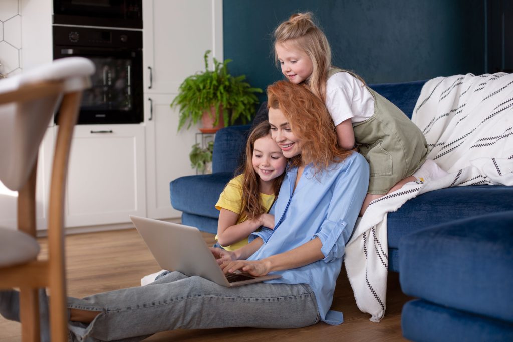 family-having-quality-time-together-2 Mother with two daughters smiling and using a laptop, illustrating Immigration Pros' family sponsorship services in Canada