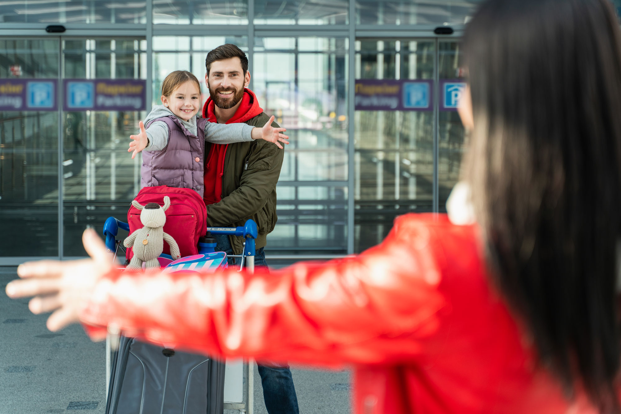 i-miss-back-view-brunette-woman-stretching-her-hands-her-husband-daughter-while-meeting-they-airport-2 Happy family reunited at the airport, showcasing the benefits of Immigration Pros' family sponsorship services in Canada