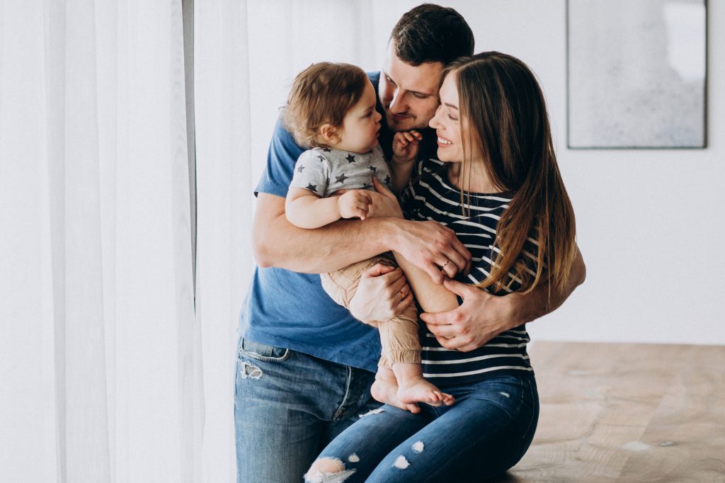 young-family-with-their-little-son-home-2 Happy parents holding their young child, representing Immigration Pros' family sponsorship services in Canada