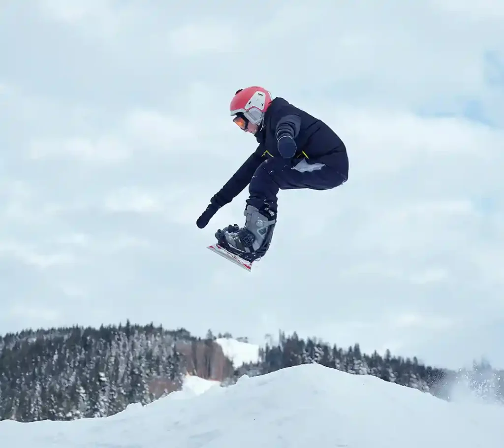 Snowboarder jumping in the snowy mountains of Canada, symbolizing tourism and adventure under the Canada Visitor Visa.